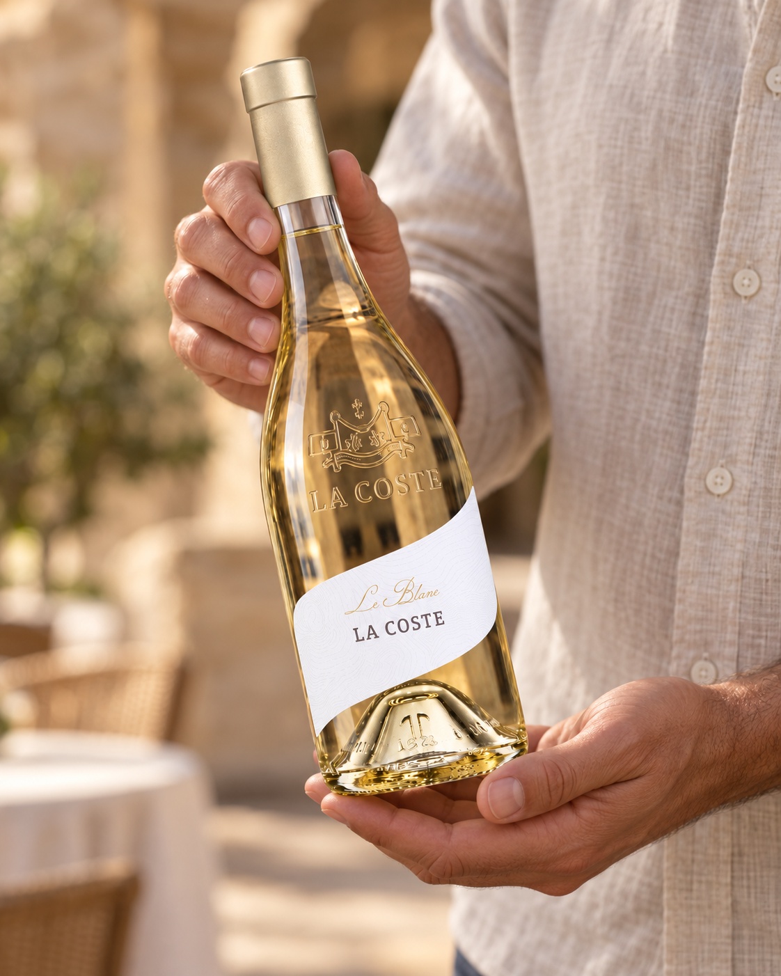 Une bouteille de Château La Coste blanc présentée à deux mains